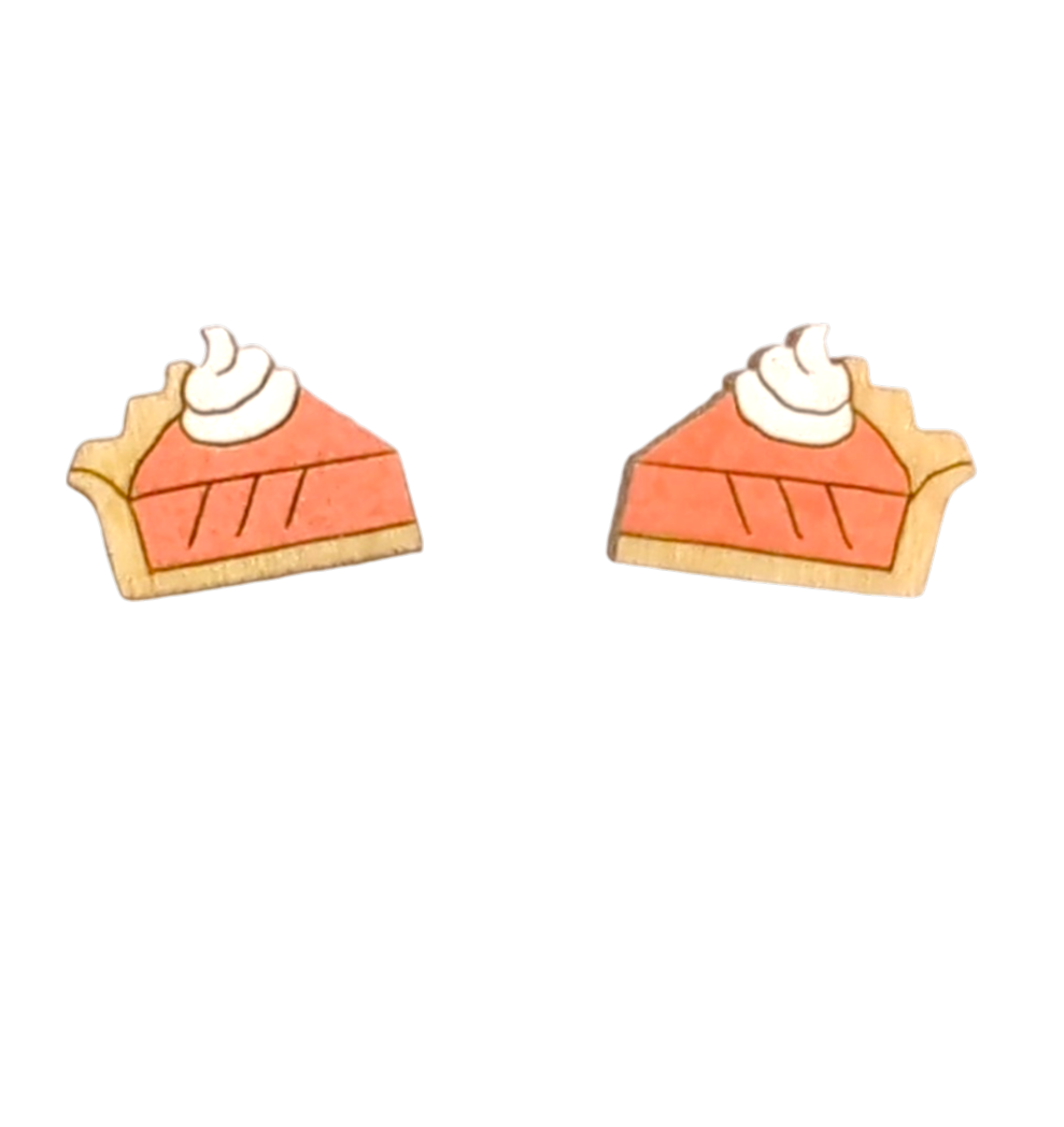 A pair of wooden stud earrings shaped like slices of pumpkin pie with orange filling, white whipped cream, and a tan crust, shown on a plain white background.
