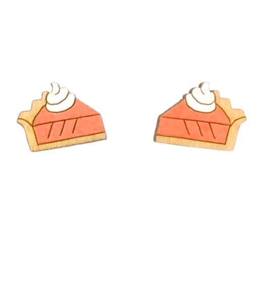 A pair of wooden stud earrings shaped like slices of pumpkin pie with orange filling, white whipped cream, and a tan crust, shown on a plain white background.
